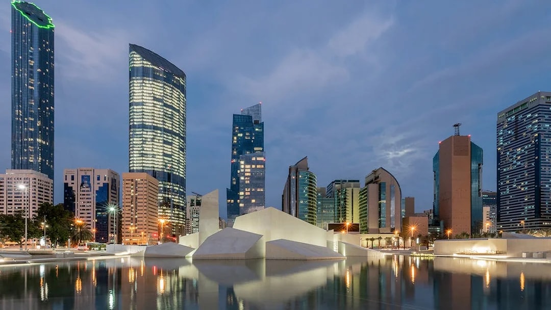 Abu Dhabi skyline with modern skyscrapers near Qasr Al Hosn at dusk.