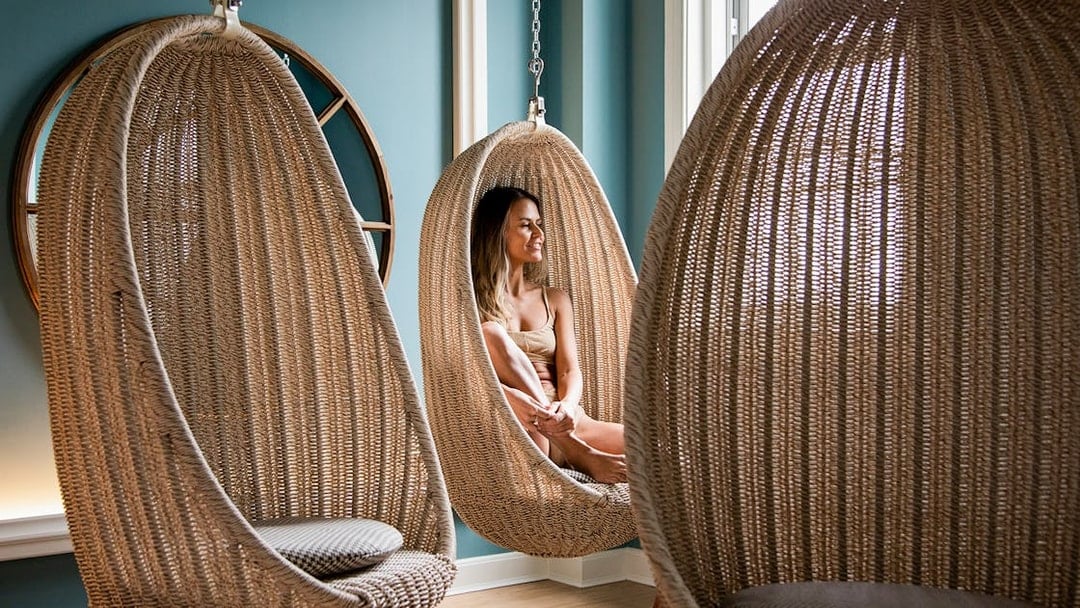 Person relaxing in a wicker hanging chair at QC New York spa.