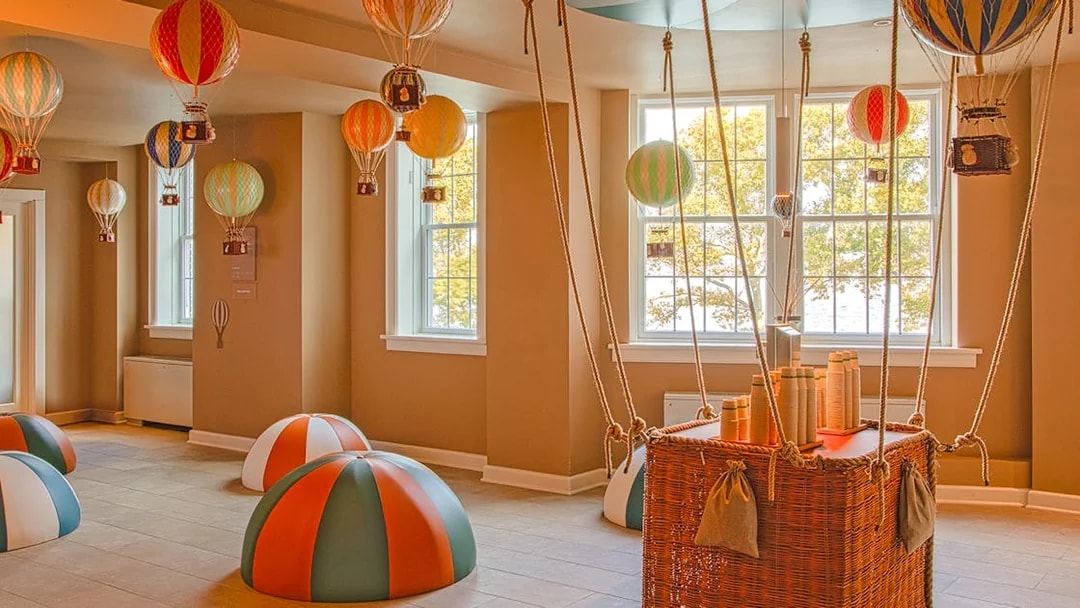Hot air balloon-themed room at QC New York with colorful decorations and wicker basket.