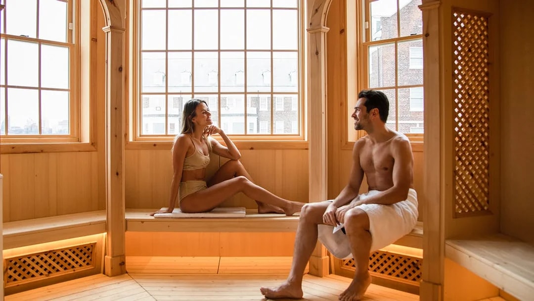 Couple relaxing in a wooden sauna at QC New York spa.