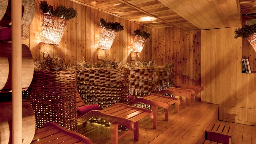 Relaxation area with wooden loungers and wicker baskets at QC Terme Pré Saint Didier.