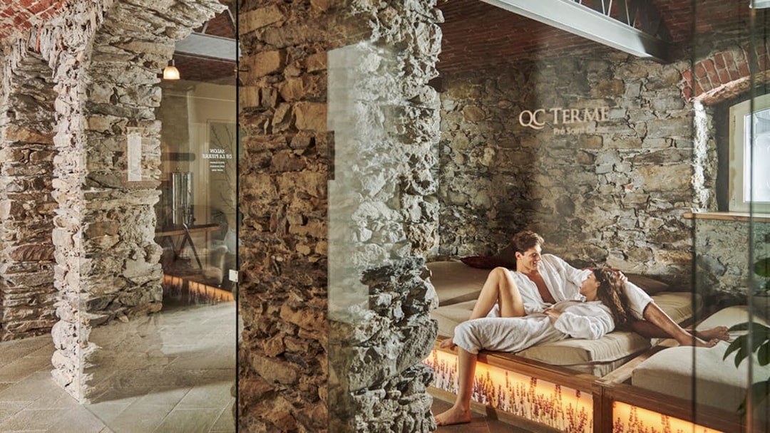 Visitors relaxing at QC Terme Prè Saint Didier Resort & Spa in a stone-walled lounge.