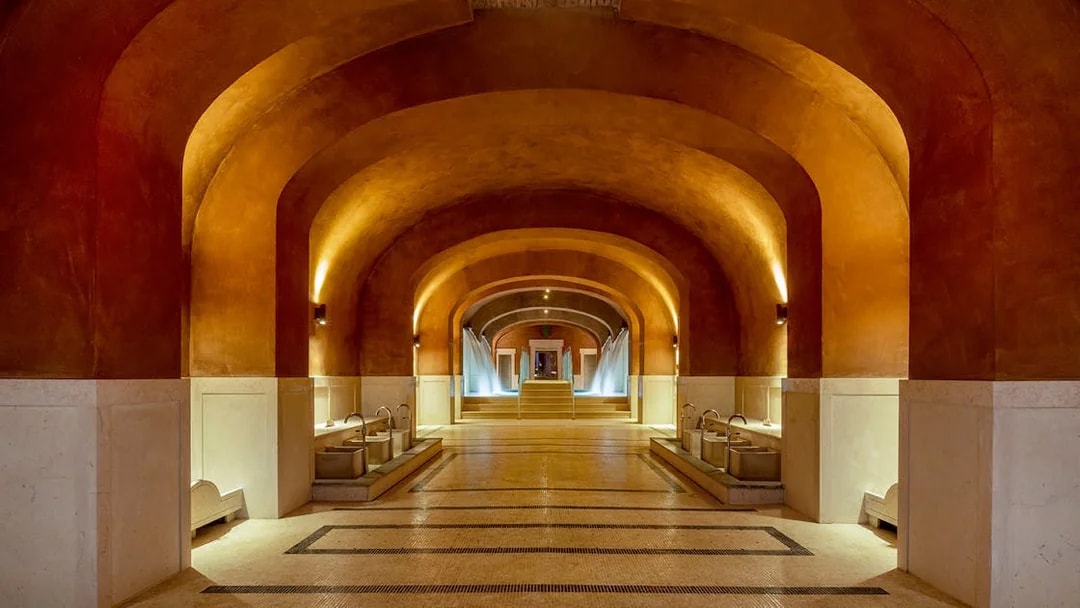 Spa interior with arched ceilings and fountains at QC Terme Roma, Italy.
