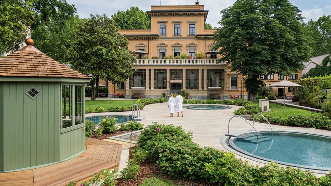 Visitors in robes walking by pools at QC TermeTorino Spa and Resort, Italy.