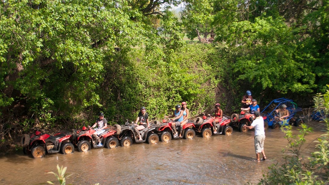 Quad riders navigating a shallow stream during a safari in Antalya.