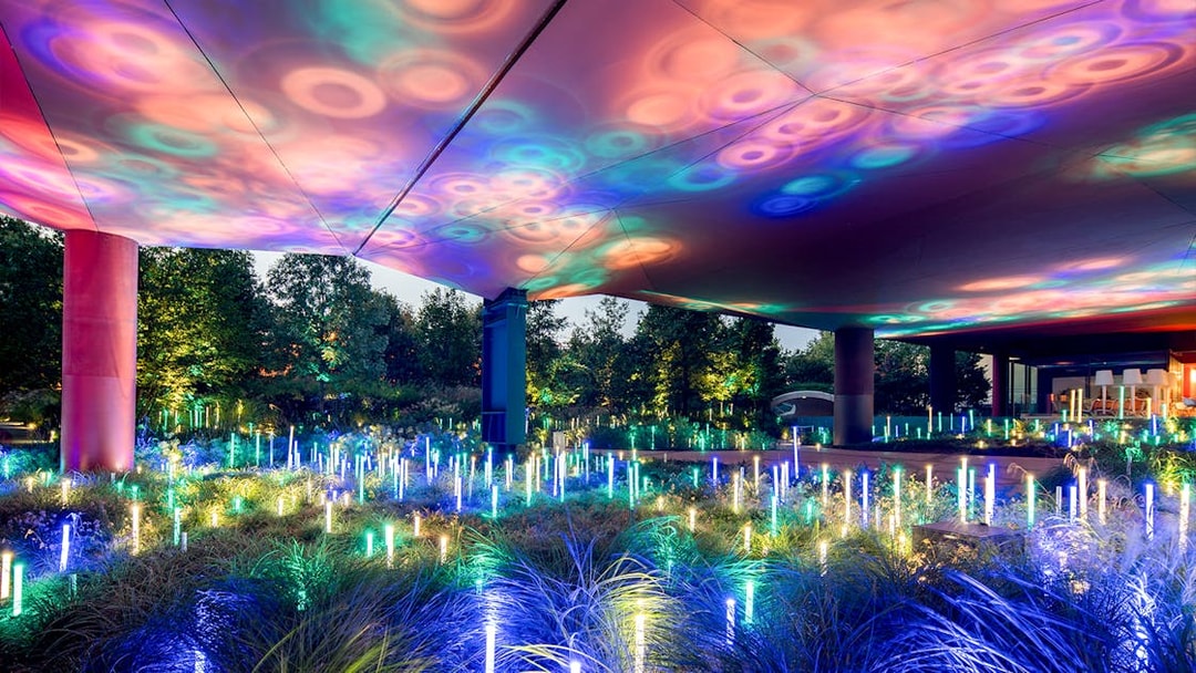 Colorful light installation at Musee du Quai Branly, Paris, illuminating garden area.