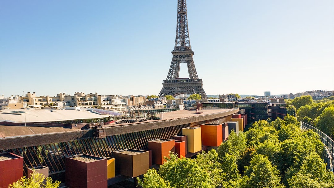 Eiffel Tower view from Musée du Quai Branly, Paris, with colorful museum facade and trees.