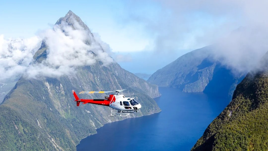Helicopter flying over cloud-covered fiords in Milford Sound, New Zealand.