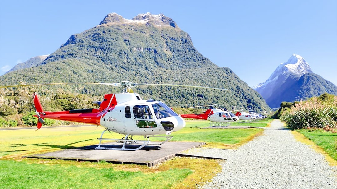 Helicopters on landing pads with Milford Sound mountains in the background.