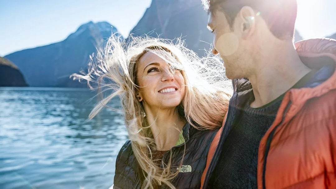 Couple enjoying a cruise on Milford Sound with mountains in the background.