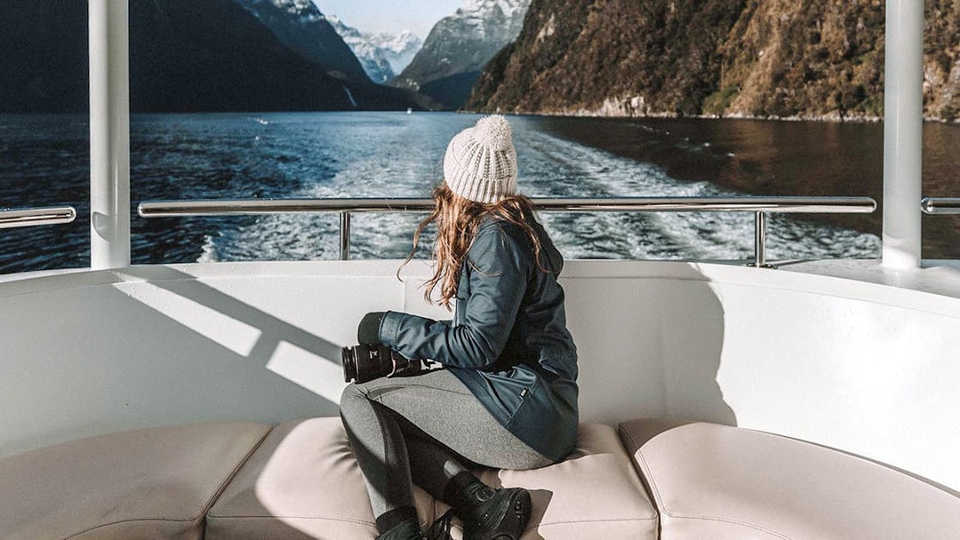 Cruise passenger enjoying Milford Sound's mountain views and lush greenery, Queenstown day trip.