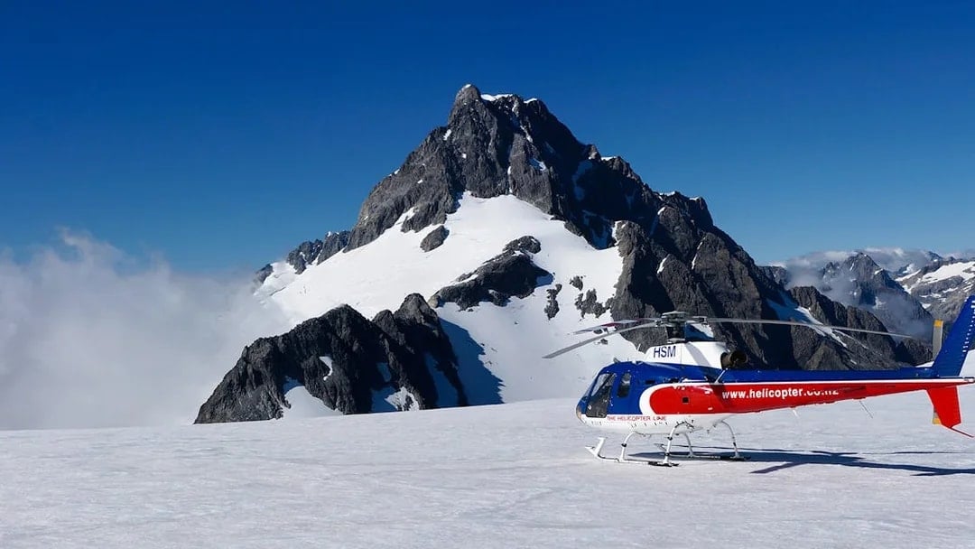 Helicopter on snowy alpine landing with mountain backdrop, Queenstown Panorama Tour.