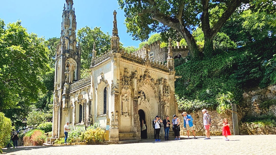 Quinta da Regaleira chapel with tourists exploring the ornate architecture in Sintra, Portugal.