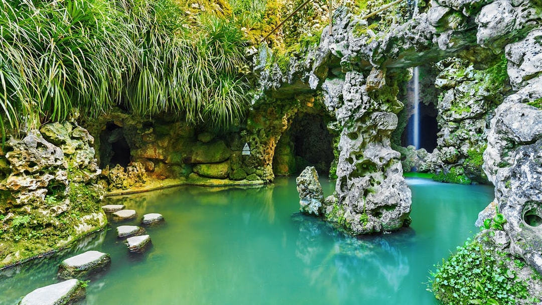 Stone pathway over turquoise water in Quinta da Regaleira garden, Sintra, Portugal.