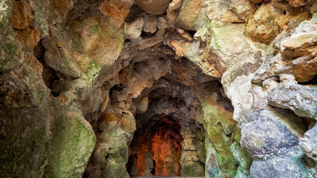 Quinta da Regaleira cave entrance surrounded by lush gardens in Lisbon.