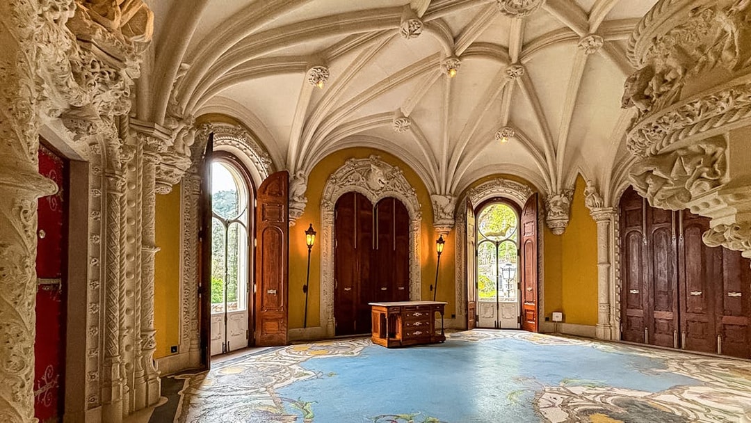 Interiors of Quinta da Regaleira with ornate ceiling and arched windows.