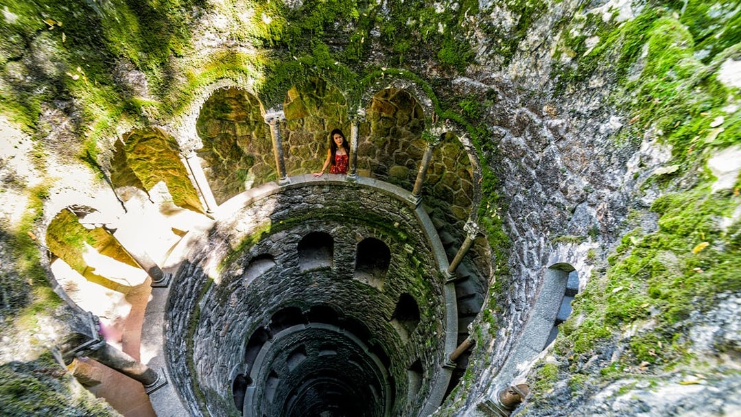 Quinta Da Regaleira initiation well with spiral staircase and stone arches in Sintra, Portugal.