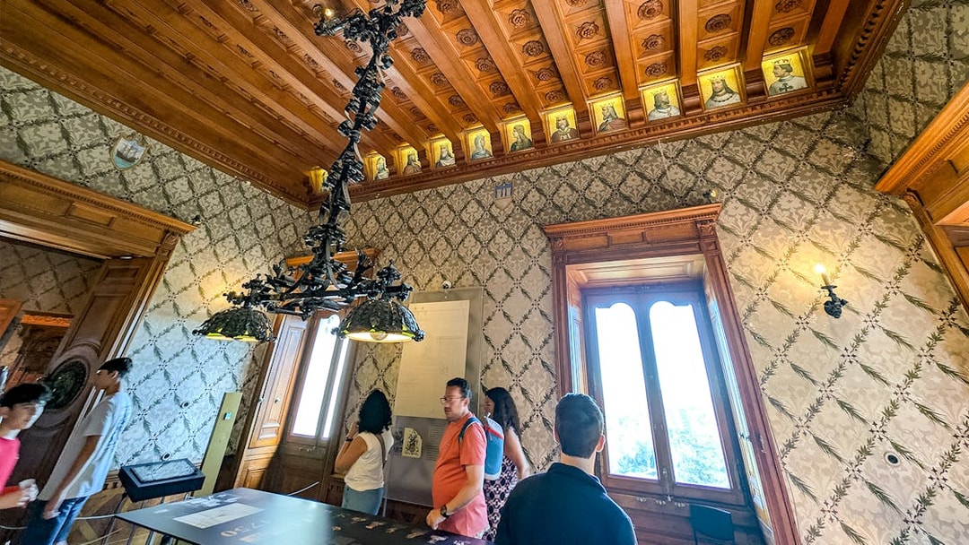 Visitors exploring an ornate room with a wooden ceiling at Quinta da Regaleira, Sintra.