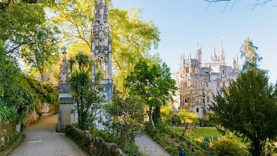 Quinta da Regaleira garden path with ornate tower and palace in Sintra, Portugal.