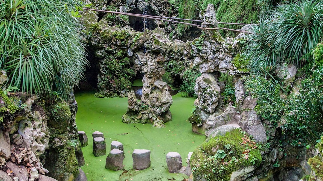 Stepping stones over green water at Waterfall Lake, Quinta da Regaleira, Sintra, Portugal.