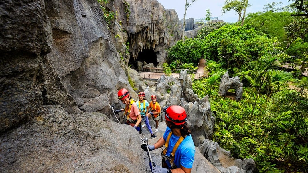 Adventurers climbing rocks in a rainforest cavern in Asia.