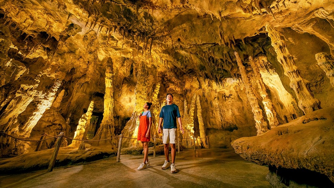 People exploring The Cavern in Rainforest Wild ASIA with stalactites and stalagmites.
