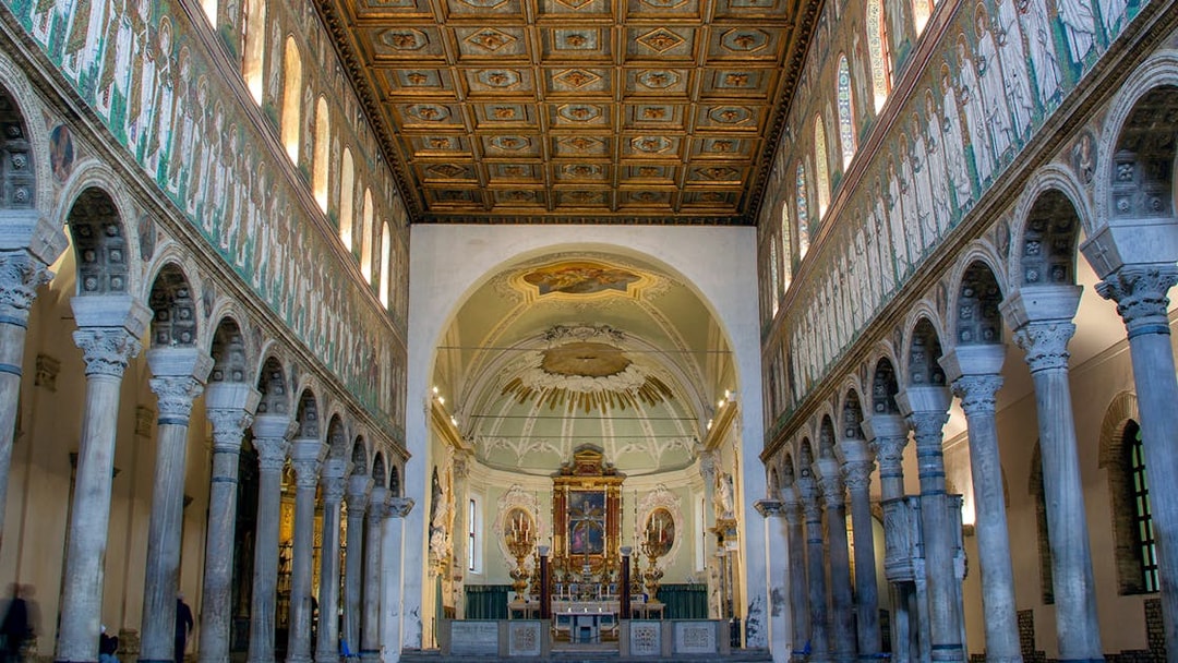 Interior of Basilica di Sant'Apollinare Nuovo in Ravenna, showcasing detailed mosaics and columns.