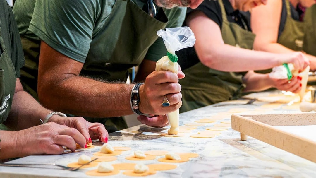 Participants shaping pasta dough in a hands-on pasta making class.
