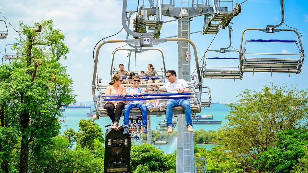 Family enjoying the Skyride over lush greenery and ocean views in Singapore.