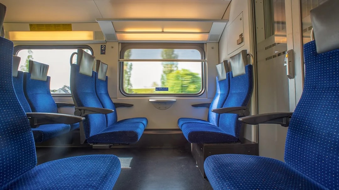 Passenger seats on Bernina train with scenic window view.
