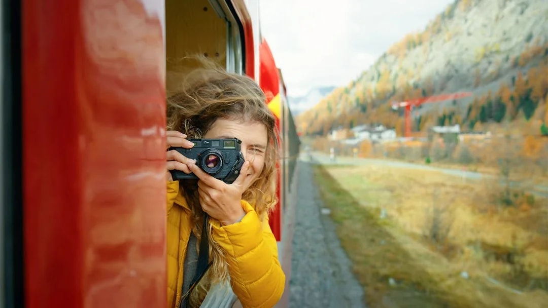 Passenger photographing scenery from Bernina train window in Switzerland.