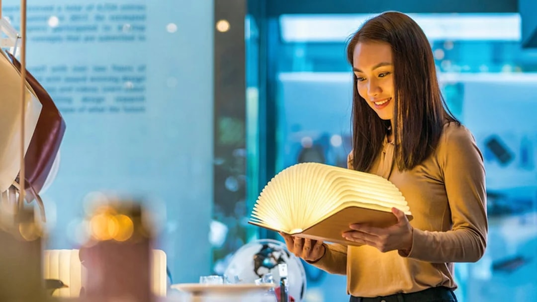 Visitor exploring illuminated book at Red Dot Design Museum, Singapore.