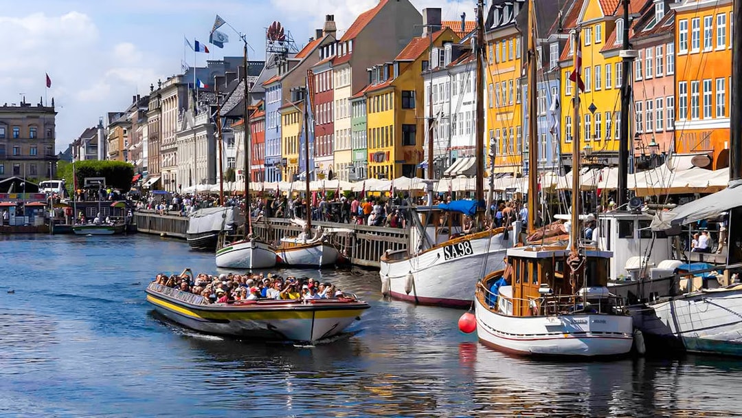 Tour boat navigating Nyhavn canal in Copenhagen with colorful buildings.