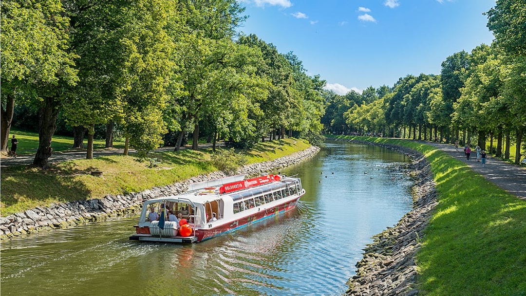 Stockholm hop-on hop-off boat cruising along a tree-lined canal.