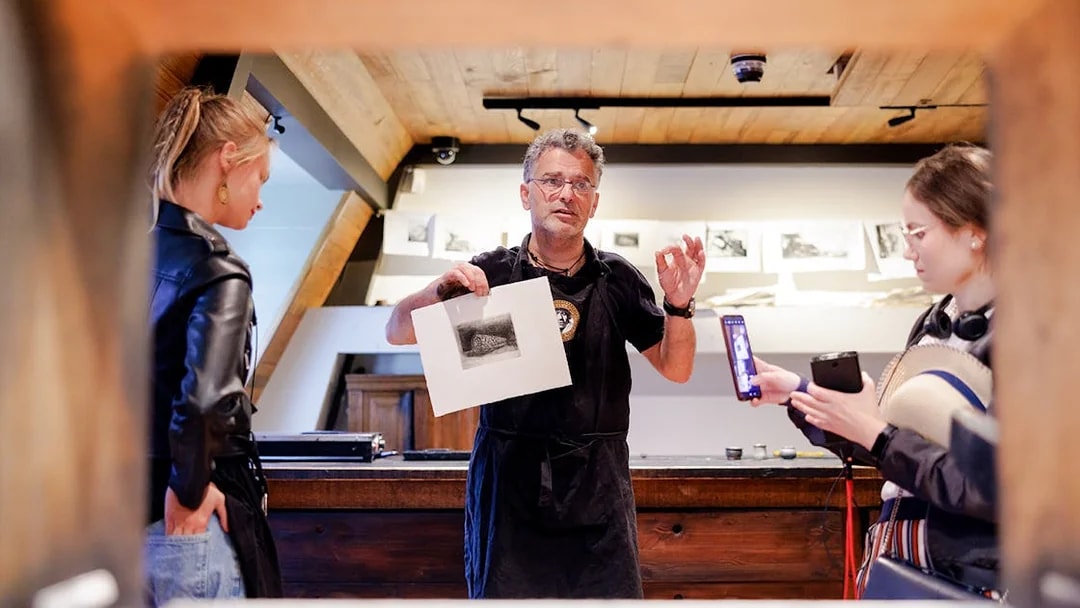 Guide explaining artwork inside Rembrandt House Museum, Amsterdam.