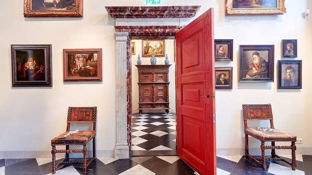 Rembrandt House Museum interior with paintings, red door, and antique furniture.