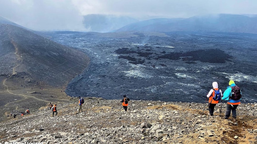 Hikers exploring volcanic terrain in Reykjanes, Iceland, with visible lava fields.