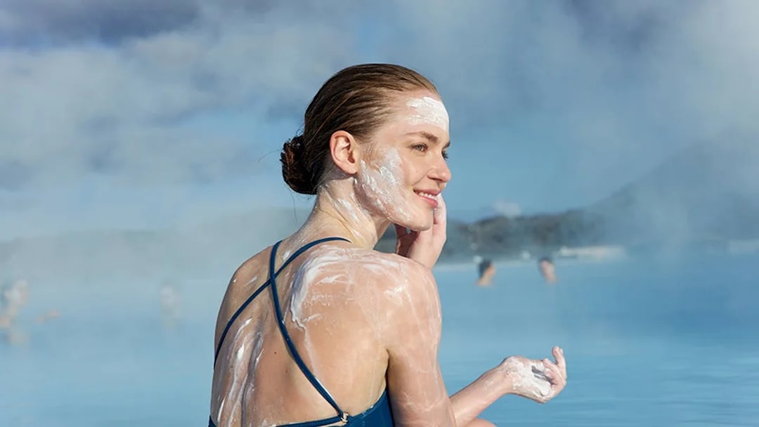Tourist applying silica mud in Blue Lagoon, Iceland.