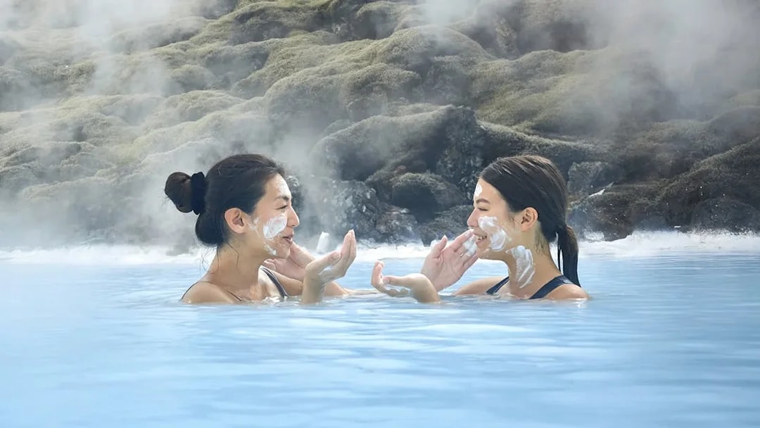 Female tourists applying face masks at Blue Lagoon, Iceland.