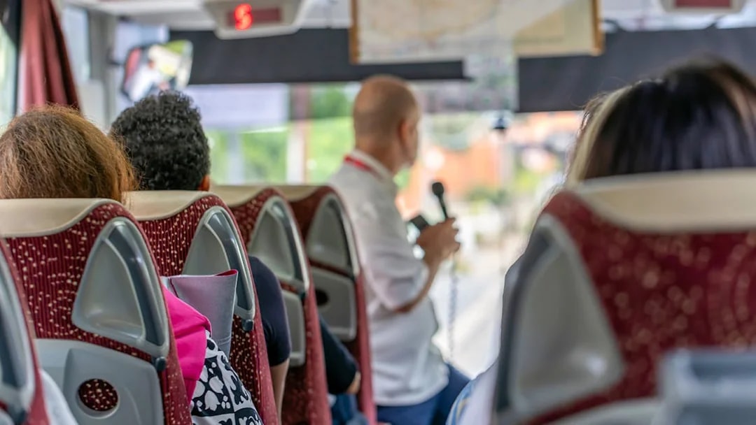Tourists on a bus listening to a guide on the Appian Way tour in Rome, Italy.