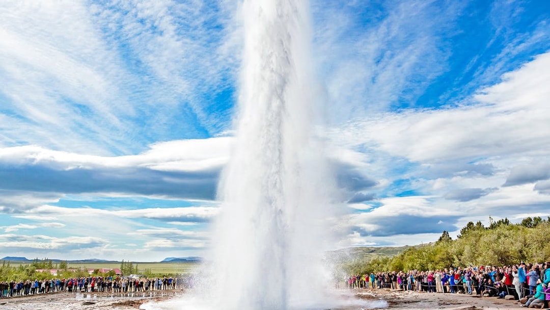 Strokkur geyser erupting in Golden Circle, Iceland, with tourists watching.