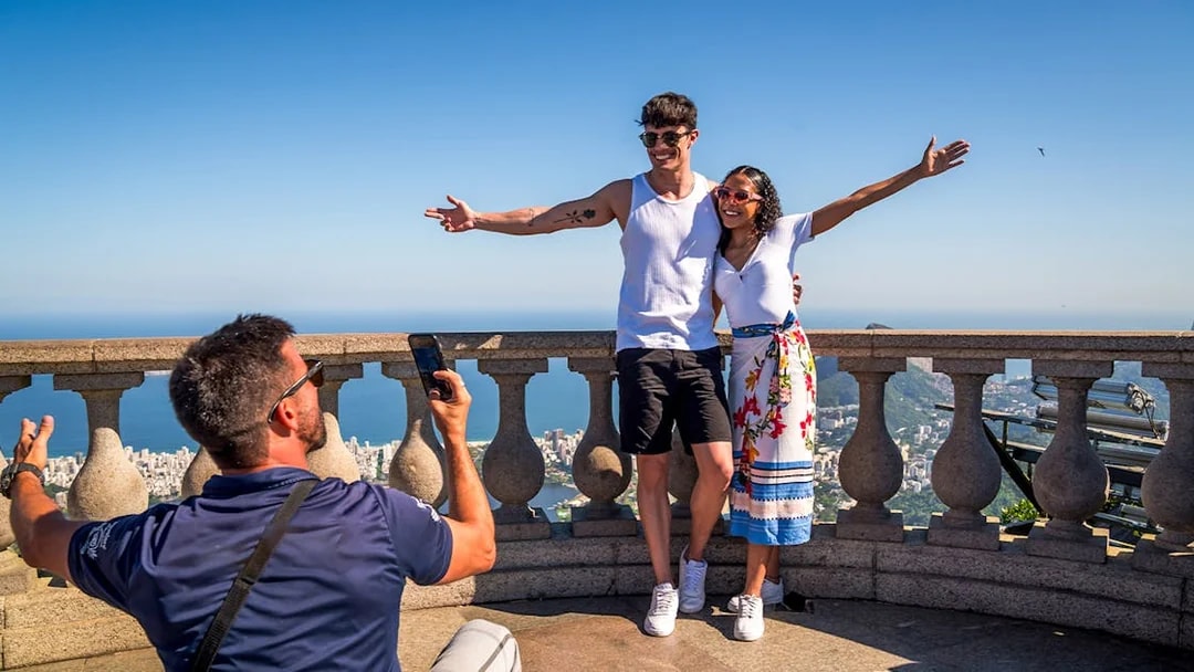 Guide photographing tourists at Christ the Redeemer, Rio de Janeiro.