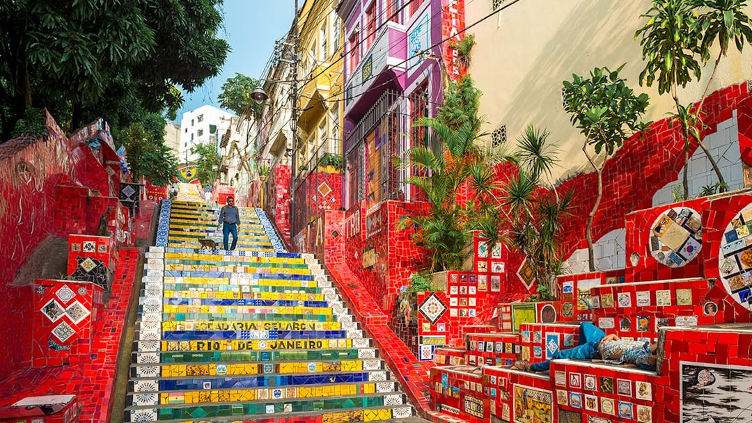 Escadaria Selarón in Rio de Janeiro with colorful mosaic tiles and a person walking.