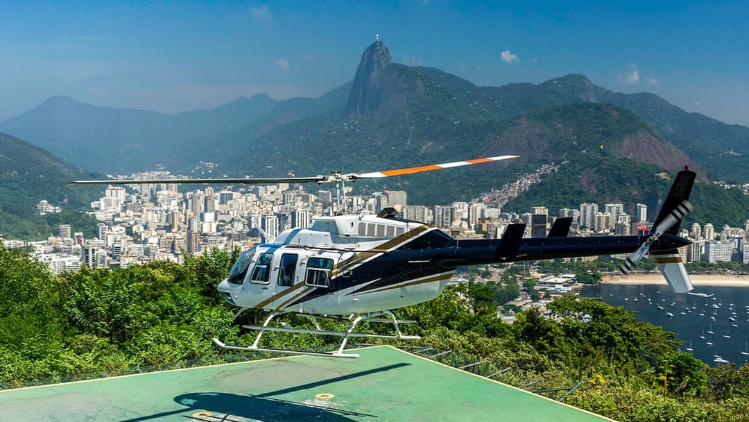 Helicopter taking off from Sugar Loaf Mountain with Rio de Janeiro cityscape in the background.