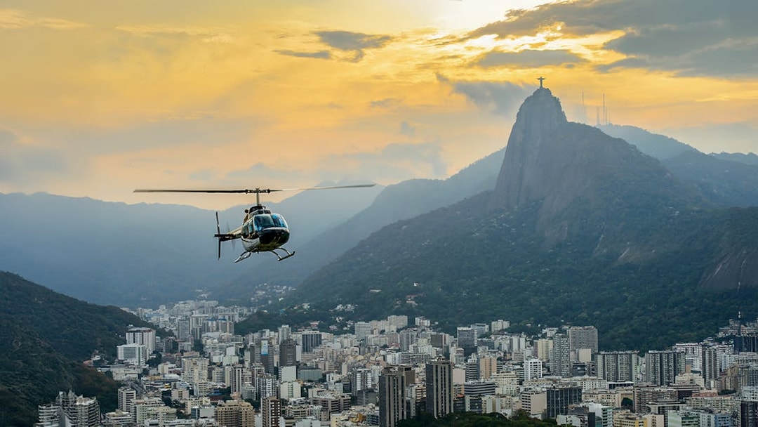 Helicopter flying over Rio de Janeiro with Christ the Redeemer at sunset.