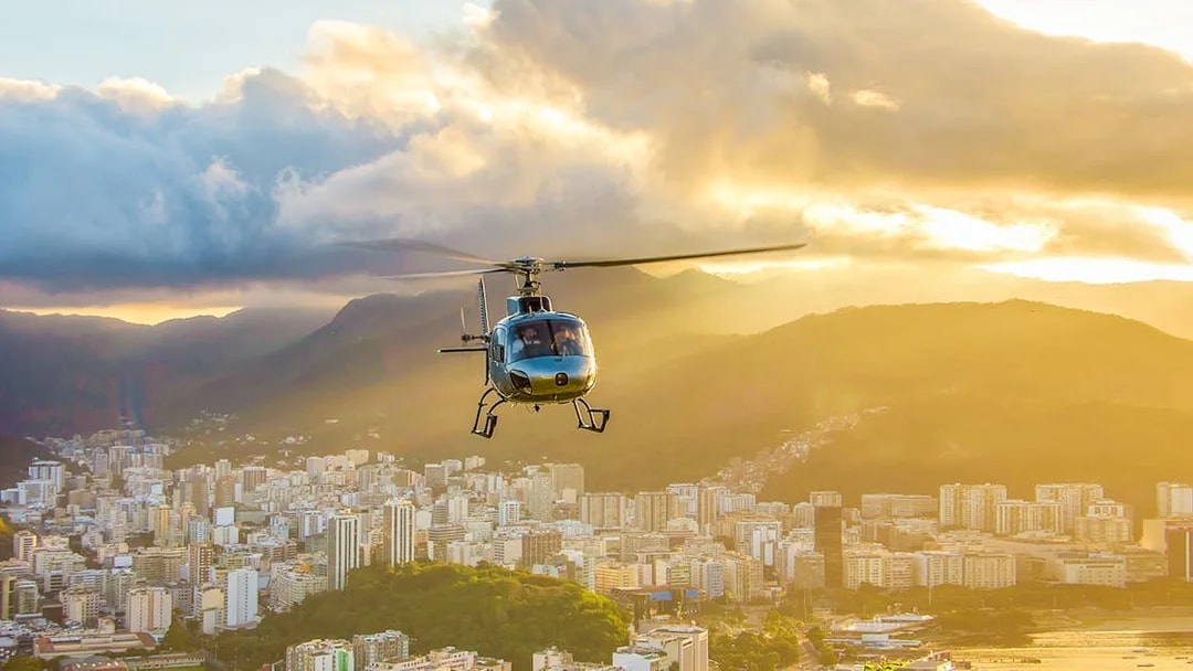 Helicopter taking off from Urca mountain helipad at sunset, overlooking Rio de Janeiro, Brazil.