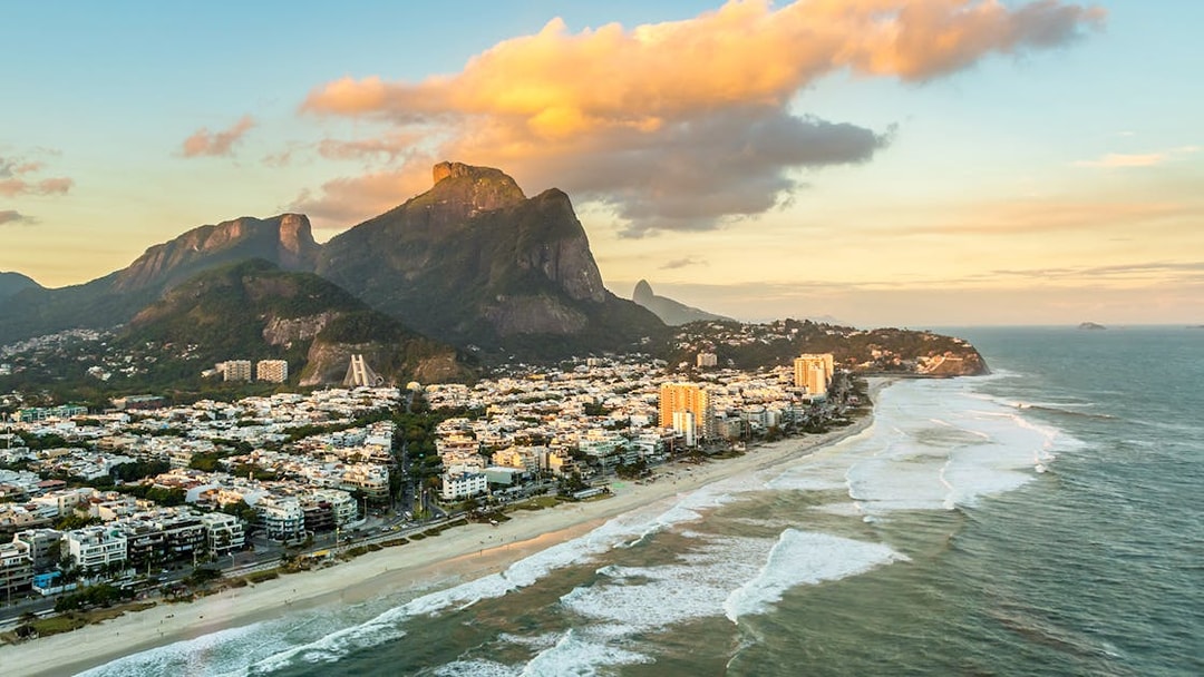 Aerial view of Rio de Janeiro coastline and mountains at sunset.
