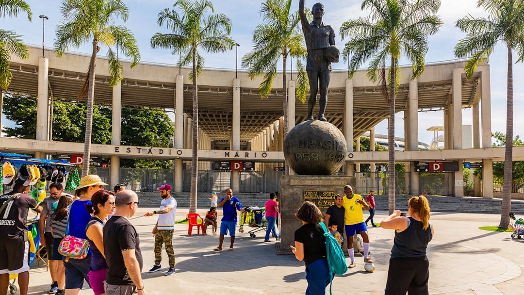 Crowd at Maracanã Stadium entrance, Rio de Janeiro, with a statue of a football player.