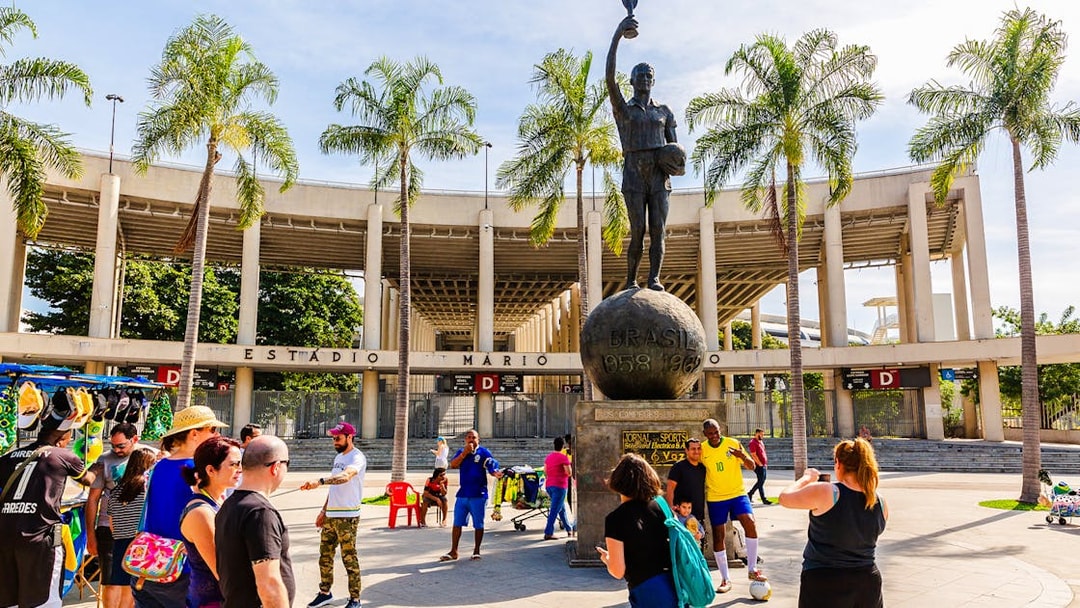 Statue of a footballer outside Maracanã Stadium, Rio de Janeiro, with tourists nearby.