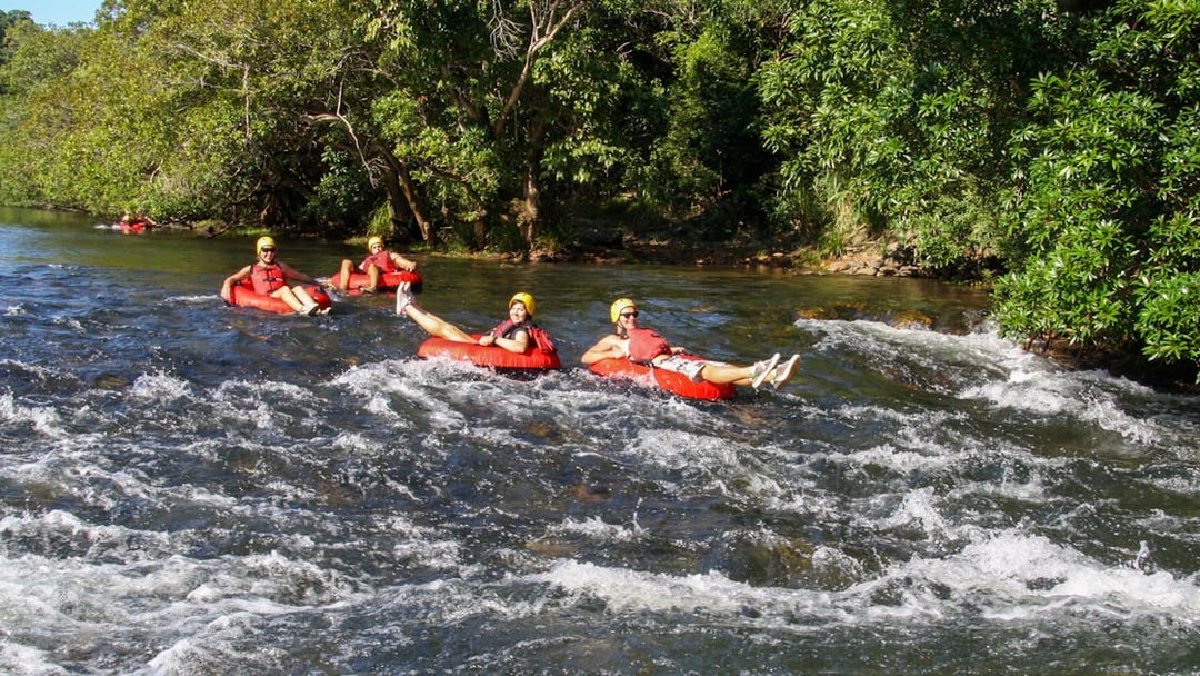 People enjoying river tubing on a scenic waterway surrounded by lush greenery.